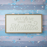 Decorative sign with 'Meet Me Under the Mistletoe' text on a white background